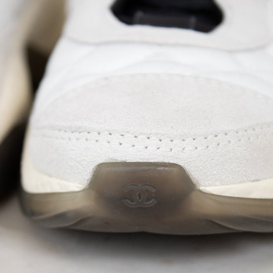Close-up of a white sneaker with a brand logo on a light background