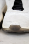 Close-up of a white sneaker with a brand logo on a light background