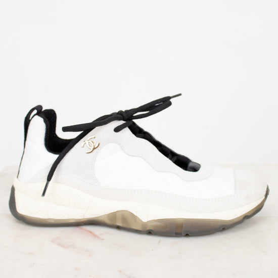 White sneaker with black laces on a light marble background