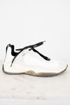 White sneaker with black laces on a light marble background