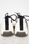 White sneakers with black laces and 'Chanel' branding on a light background
