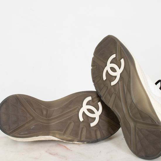 Pair of black shoes with gray soles and white logo on a light background