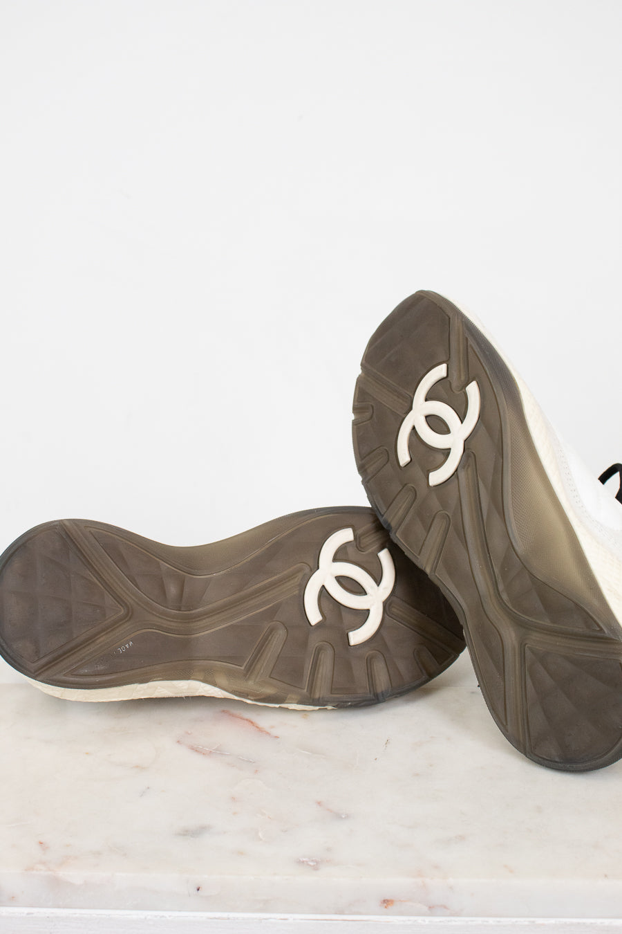 Pair of black shoes with gray soles and white logo on a light background
