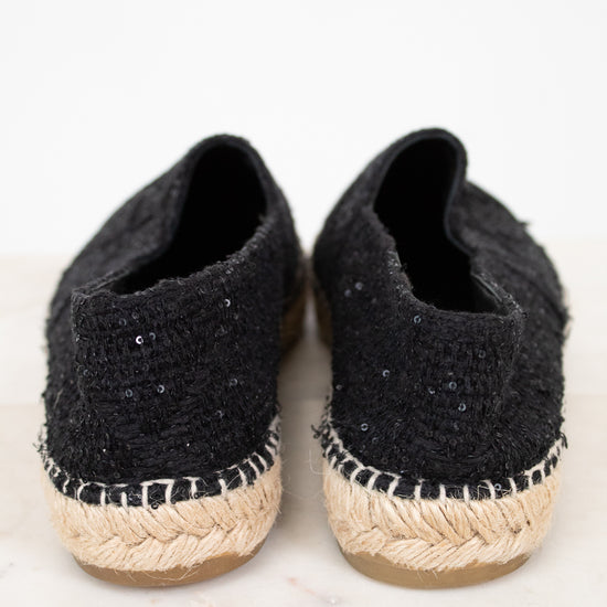 Pair of black espadrille shoes with jute sole on a light background