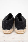 Pair of black espadrille shoes with jute sole on a light background