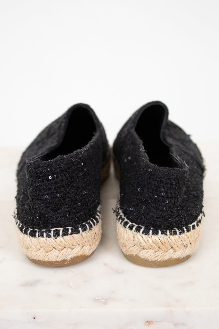 Pair of black espadrille shoes with jute sole on a light background