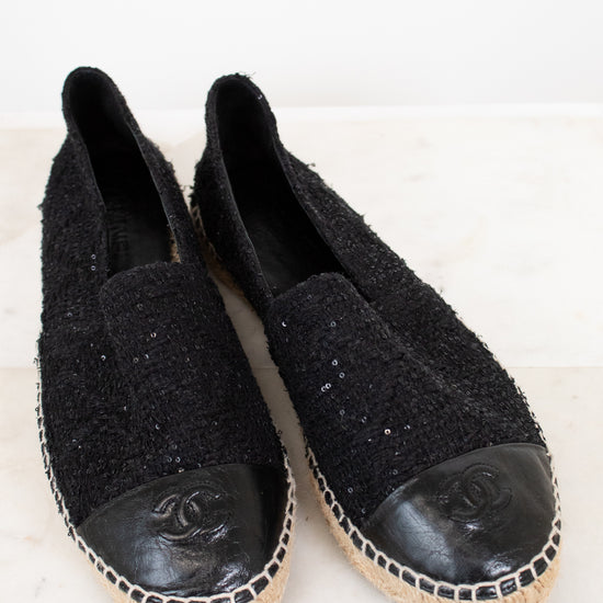 Pair of black Chanel espadrilles on a white background