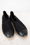 Pair of black Chanel espadrilles on a white background