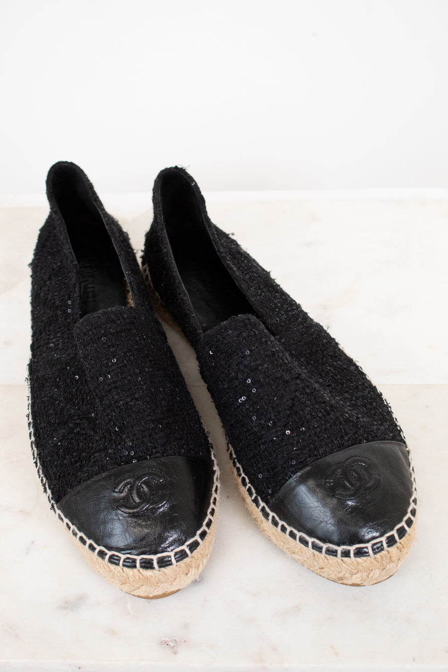 Pair of black Chanel espadrilles on a white background