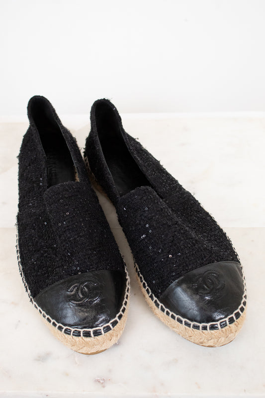 Pair of black Chanel espadrilles on a white background