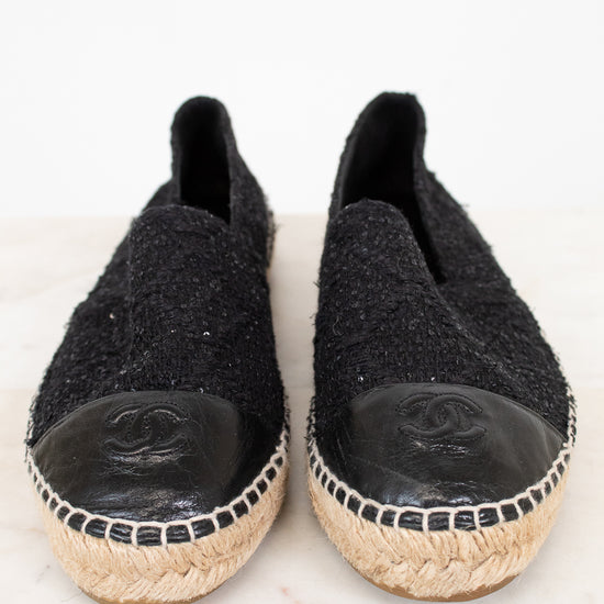 Pair of black espadrilles with Chanel logo on a white background
