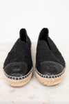 Pair of black espadrilles with Chanel logo on a white background