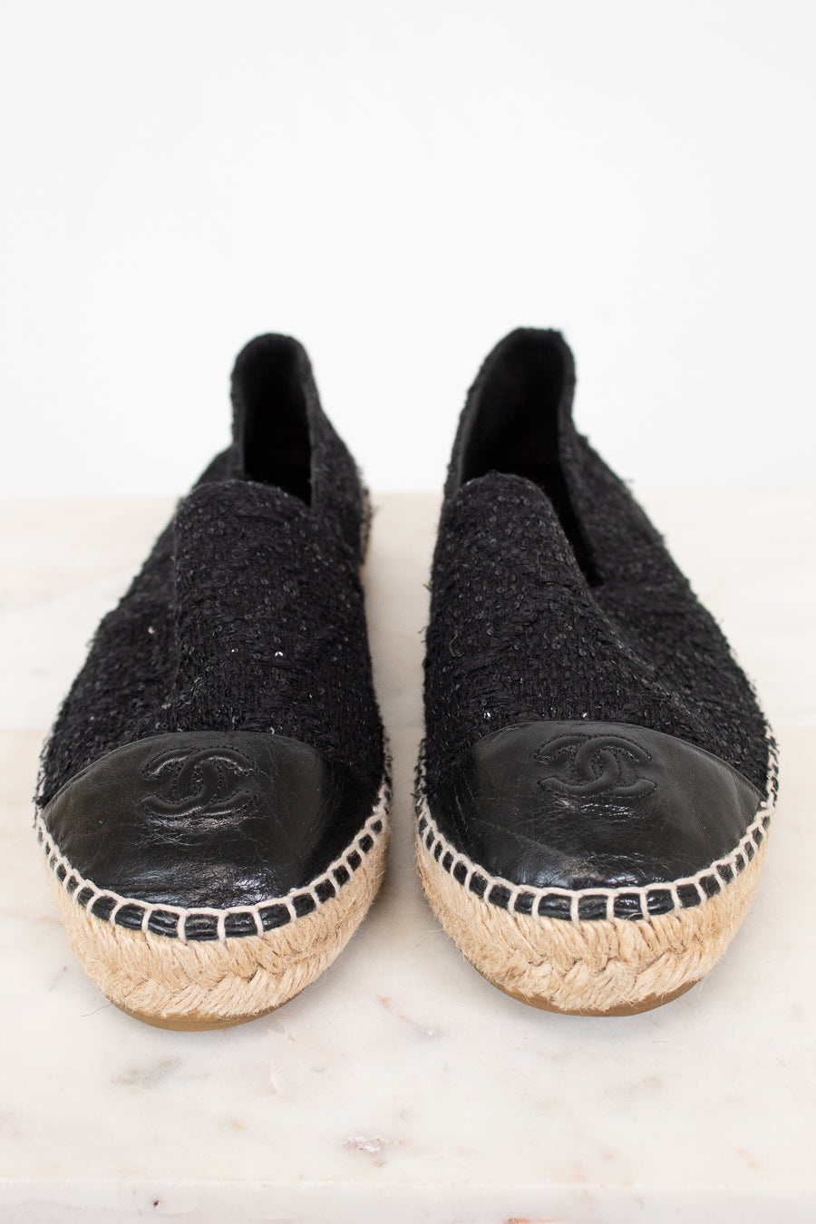 Pair of black espadrilles with Chanel logo on a white background