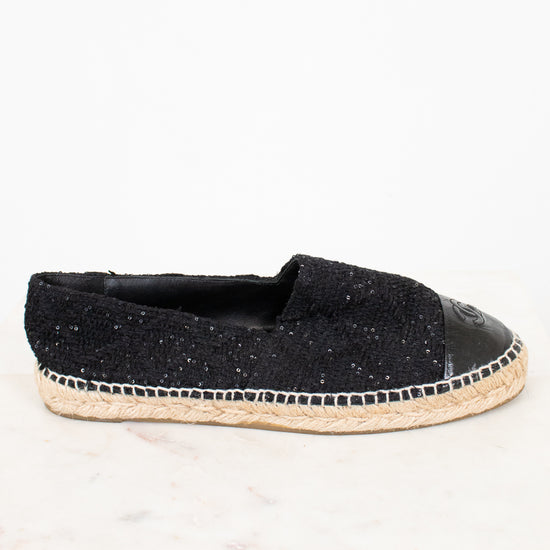 Side view of black espadrilles with jute soles on white background.