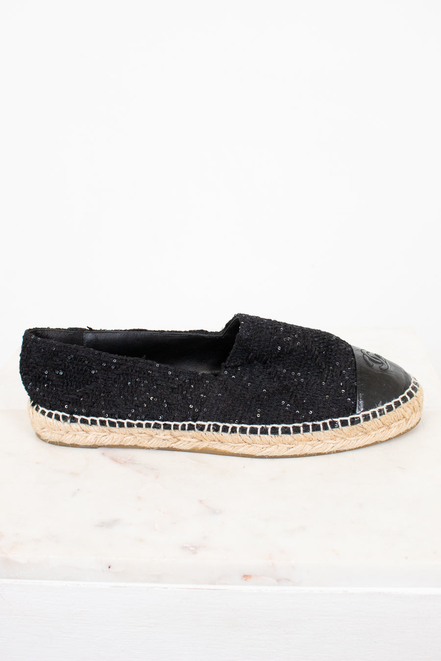 Side view of black espadrilles with jute soles on white background.