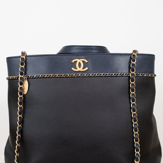 Black handbag with gold chain and Chanel logo on a white background