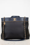 Black handbag with gold chain and Chanel logo on a white background