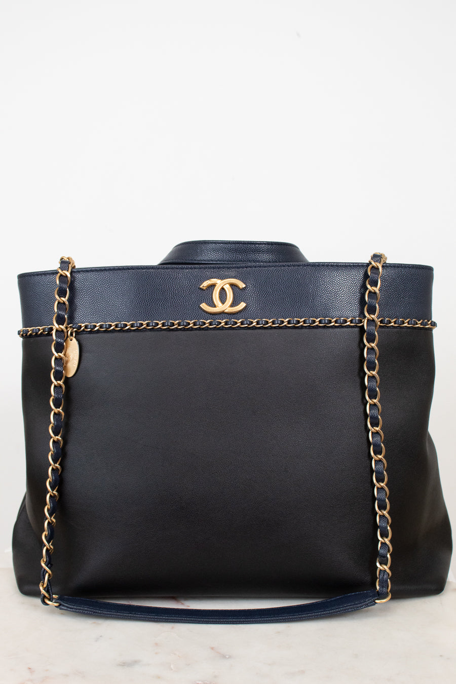 Black handbag with gold chain and Chanel logo on a white background