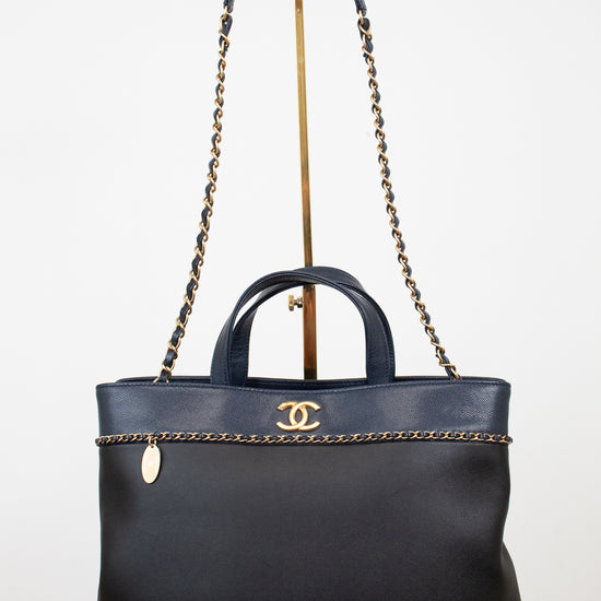 Black handbag with gold chain detail on a white background