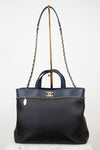 Black handbag with gold chain detail on a white background