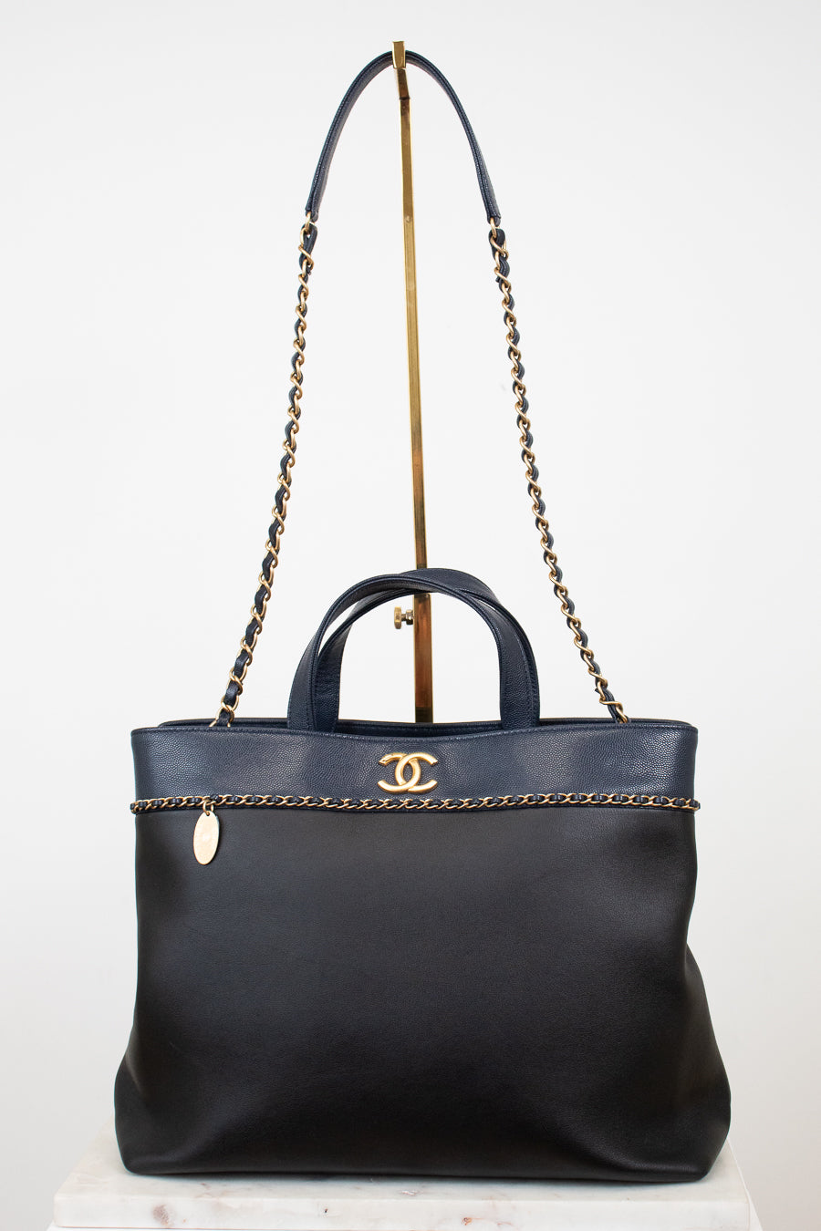 Black handbag with gold chain detail on a white background