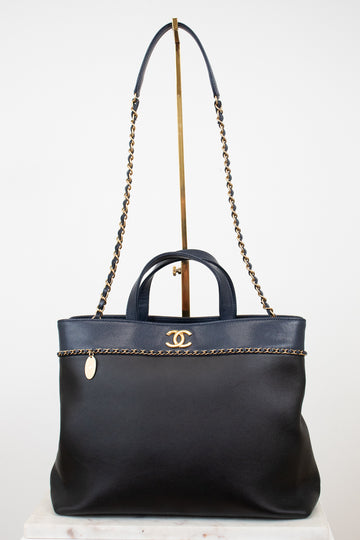 Black handbag with gold chain detail on a white background