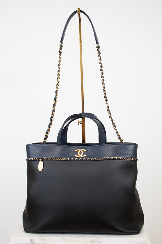 Black handbag with gold chain detail on a white background