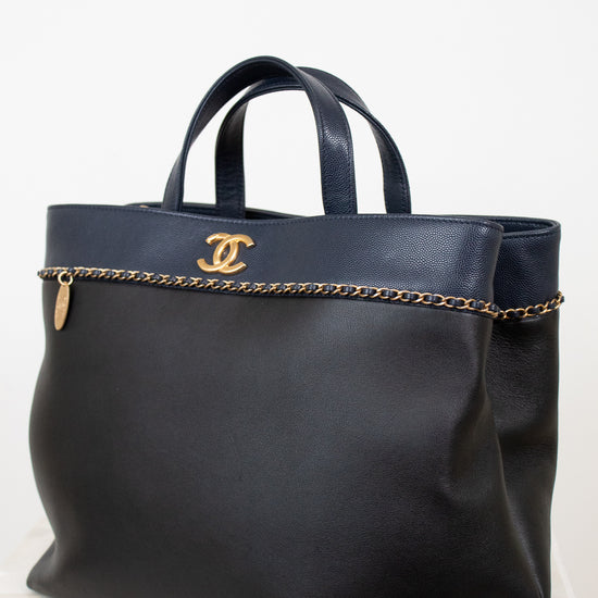 Black handbag with gold chain detail and logo on a white background