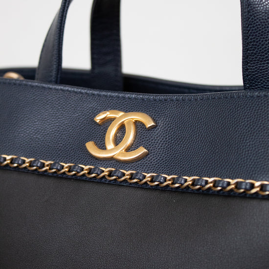 Black handbag with gold chain detail and logo on a white background