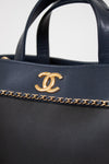 Black handbag with gold chain detail and logo on a white background