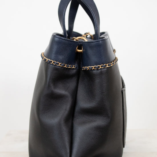 Black leather handbag with gold chain detail on a white background