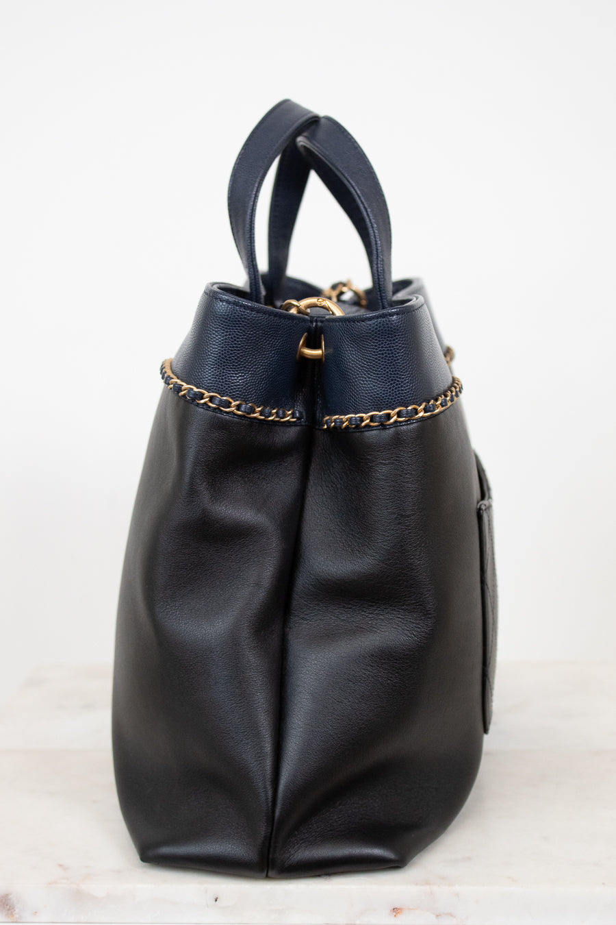 Black leather handbag with gold chain detail on a white background