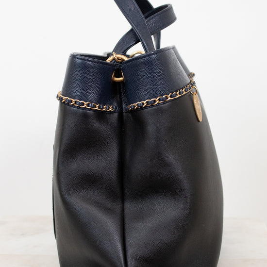 Black leather handbag with gold chain detail on a white background