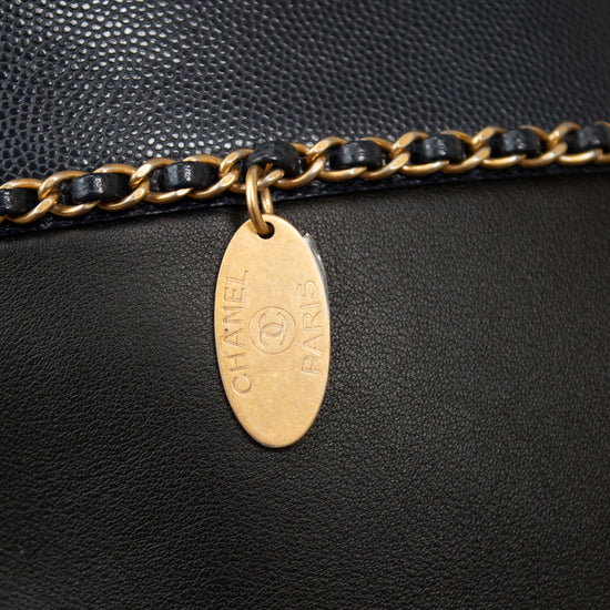 Close-up of a black leather handbag with a gold chain and tag, featuring the Chanel logo.