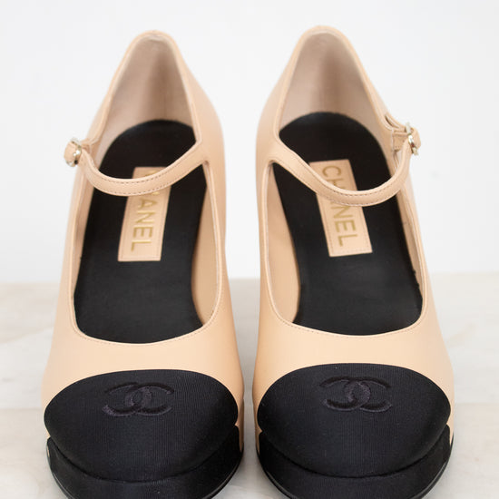 Pair of beige high-heeled shoes with black details on a light background