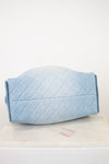 A light blue quilted fabric cover or pouch with a diamond stitched pattern, resting on a white marble surface against a plain white background.