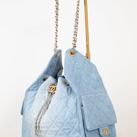A light blue quilted Chanel shoulder bag with gold-tone hardware, shown on a white surface against a white background.