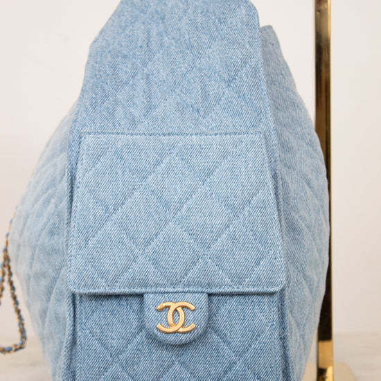 A light blue quilted denim shoulder bag with a gold-tone interlocking CC logo on the front flap, displayed against a light background.
