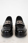 Pair of black loafers with silver CC logo on a white background