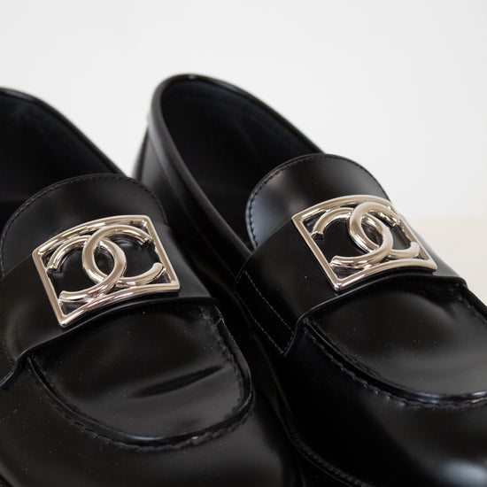 Black loafers with gold CC logo on a white background