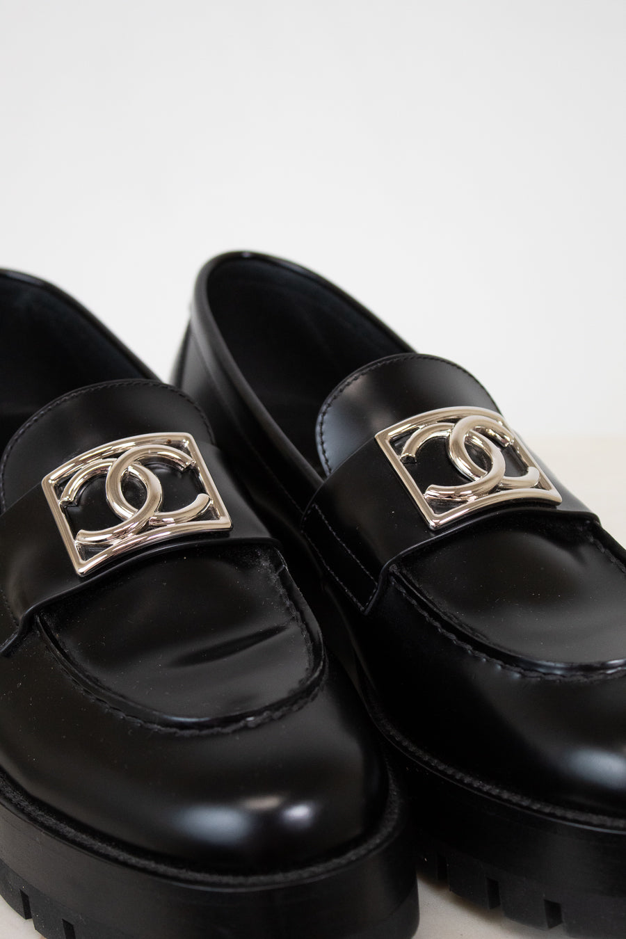 Black loafers with gold CC logo on a white background