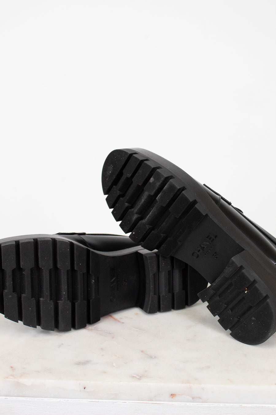 Close-up of black shoes soles on a marble surface