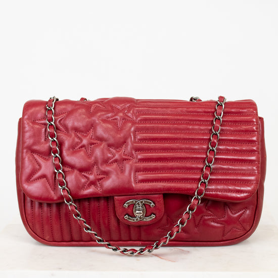 Red quilted handbag with a chain strap on a white background
