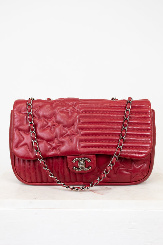 Red quilted handbag with a chain strap on a white background