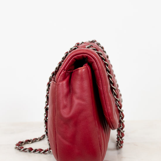 Side view of red leather handbag on white background