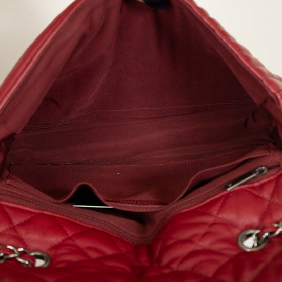 Red quilted handbag with a hand holding it open, showing the interior.