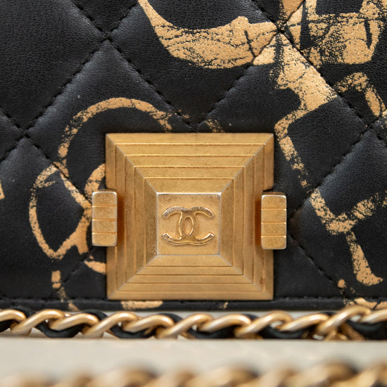 Close-up of a Chanel handbag with gold chain and quilted black and gold pattern.