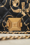 Close-up of a Chanel handbag with gold chain and quilted black and gold pattern.