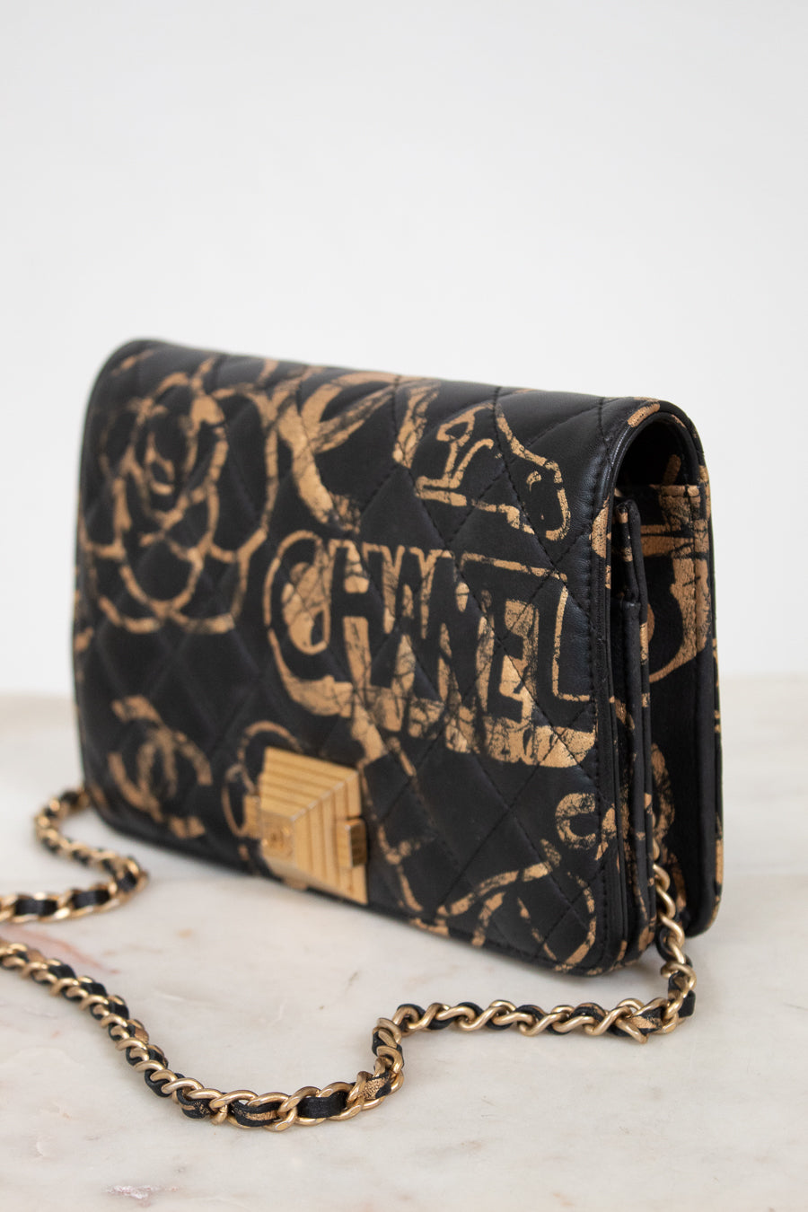 Black Chanel handbag with gold chain on a white background