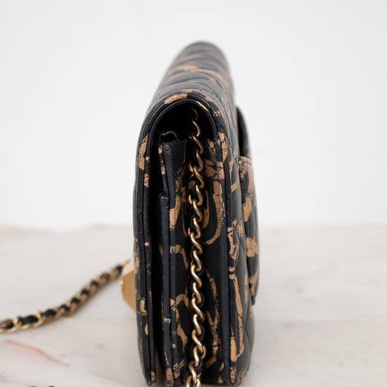 Black handbag with gold chain strap on a white background